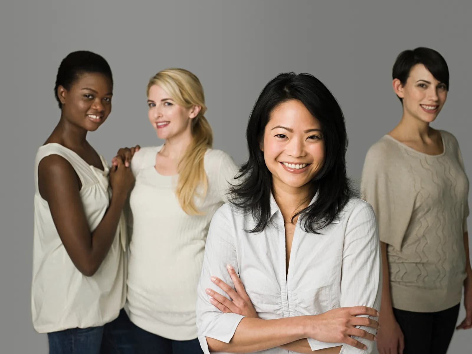 Four women standing together, smiling, representing voices in women's health